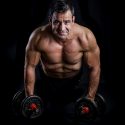 Man posing for a fitness photographer holding a plank with dumbbells